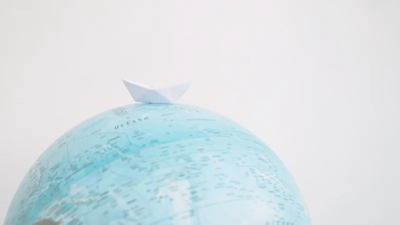 Una barchetta di carta posata sulla sommità di un mappamondo